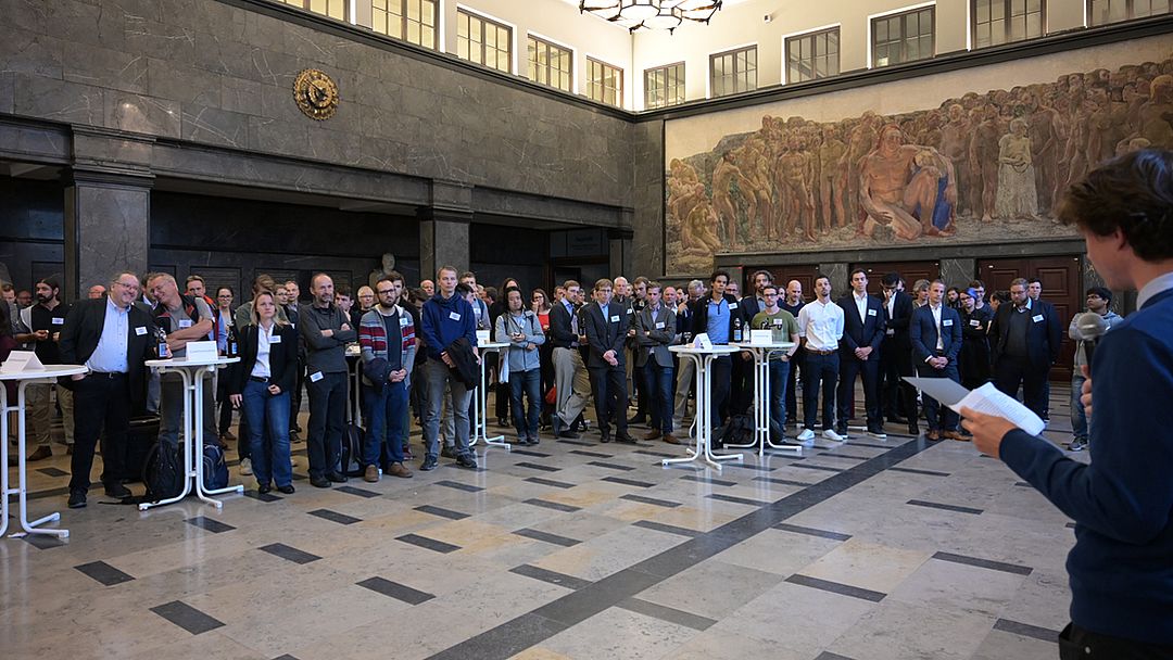 Viele Menschen an Stehtischen in einer Halle